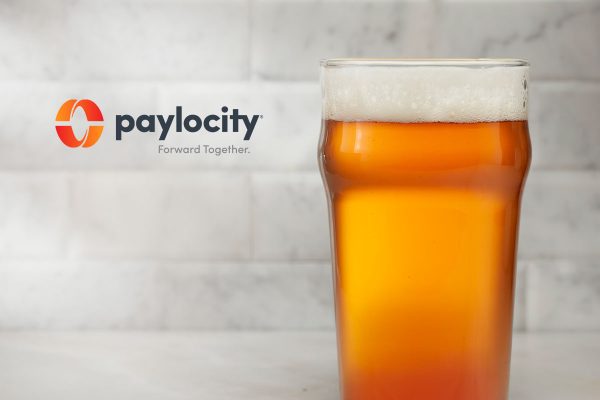 nonic pint filled with beer next to Paylocity logo