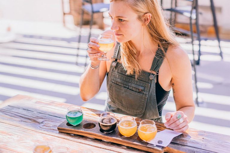 woman considering beer sample in taster flight