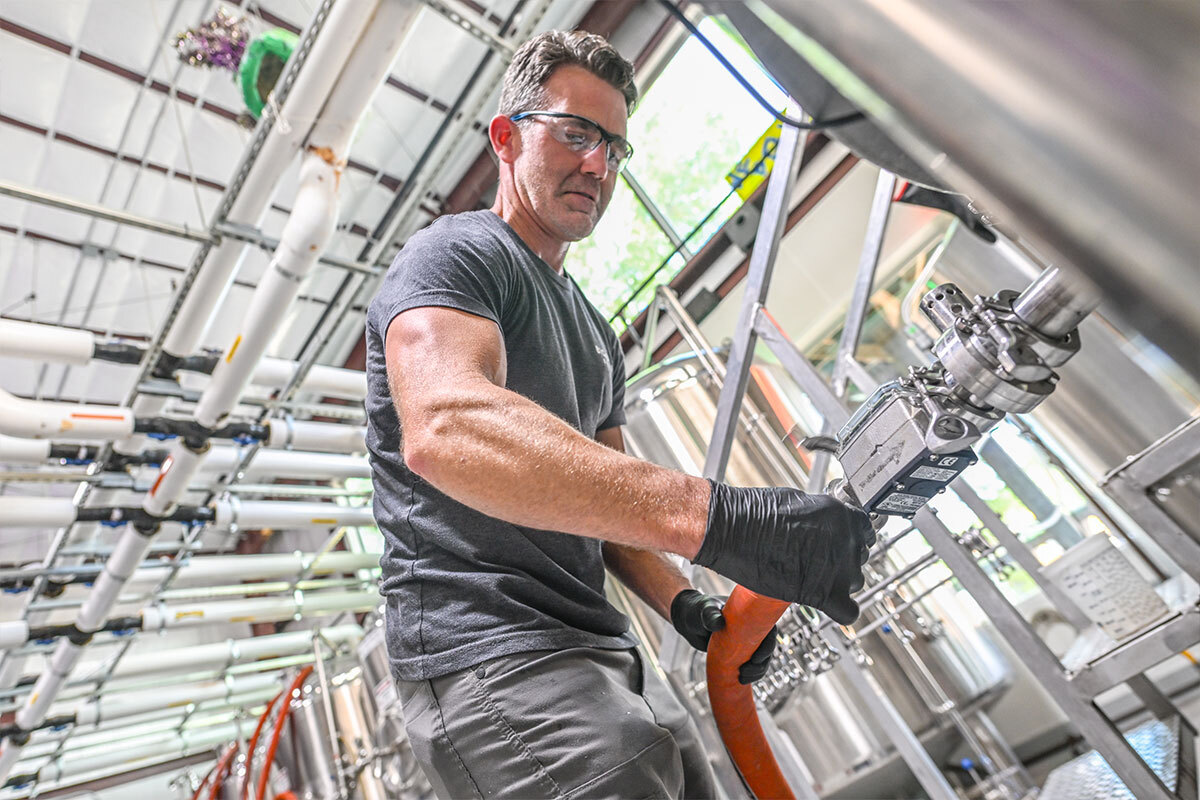 Brewer hooking up hose in brewhouse