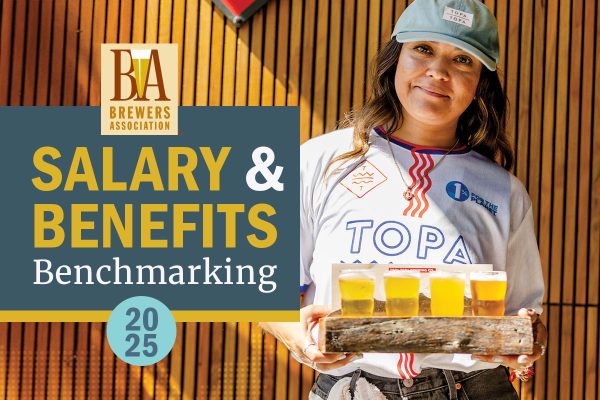 woman smiling at the camera holding beer tasters
