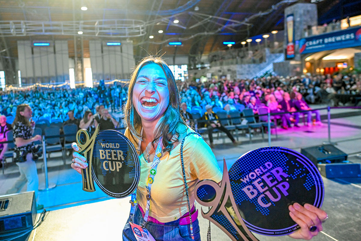 A woman poses with two World Beer Cup awards
