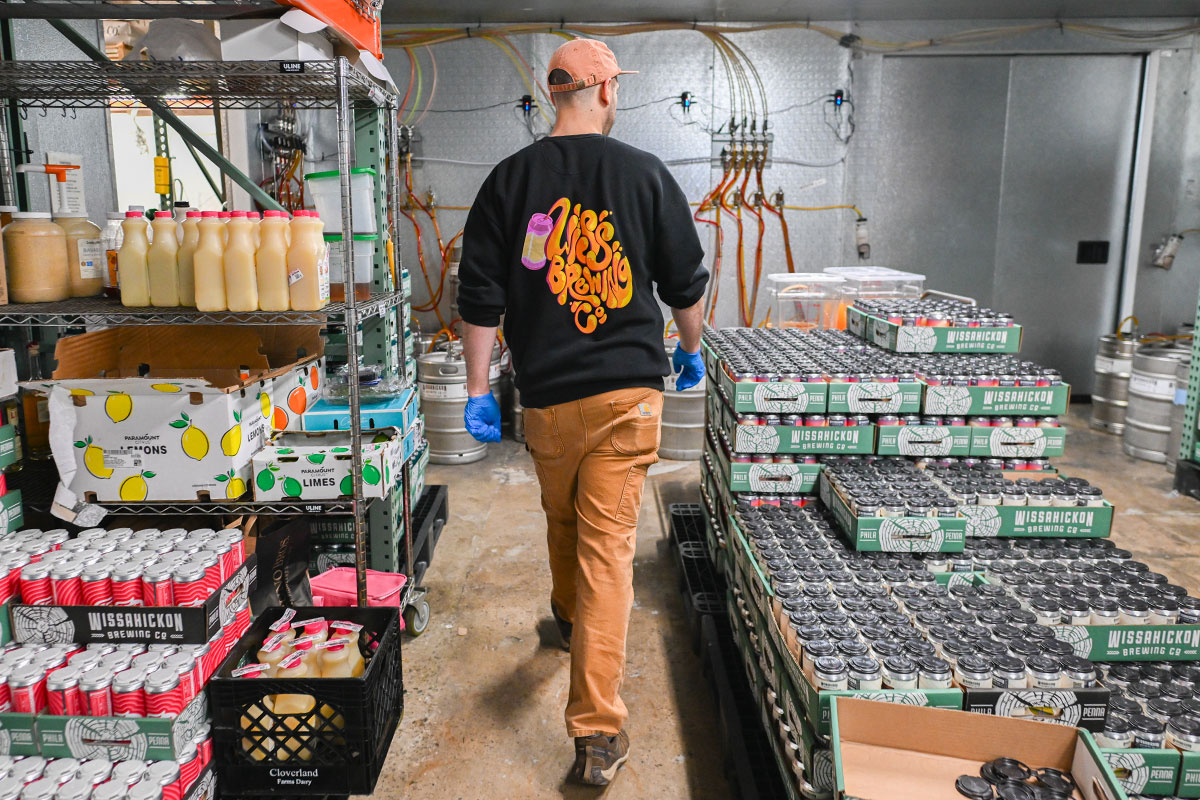 Brewer walking amid pallets of canned beer