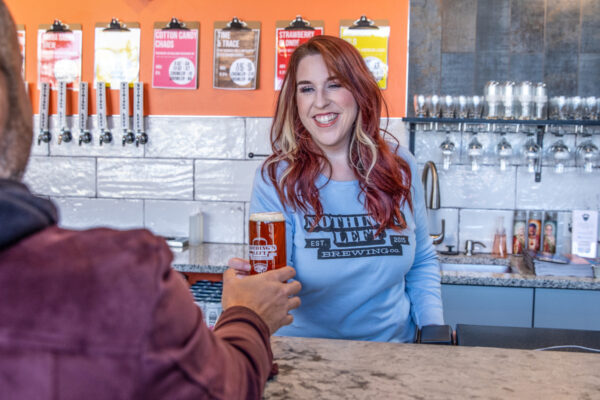 taproom bartender handing customer a beer