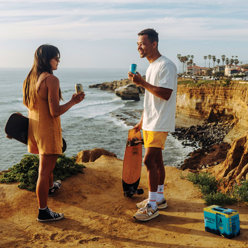 Promotional still of two young people on a coastal bluff with skateboards and Athletic beers