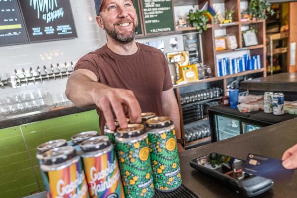 Taproom bartender ringing up beer to-go as customer pays with credit card