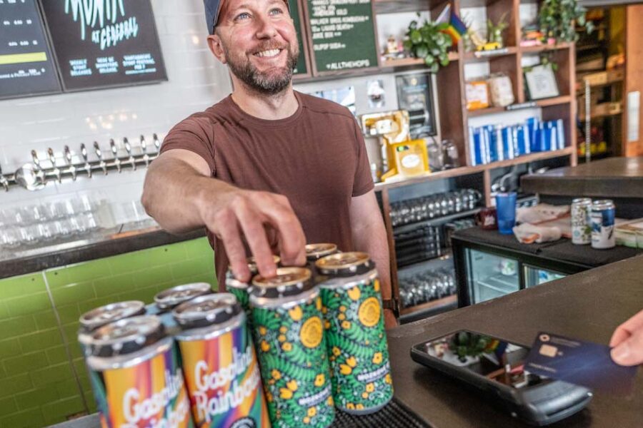 Taproom bartender ringing up beer to-go as customer pays with credit card