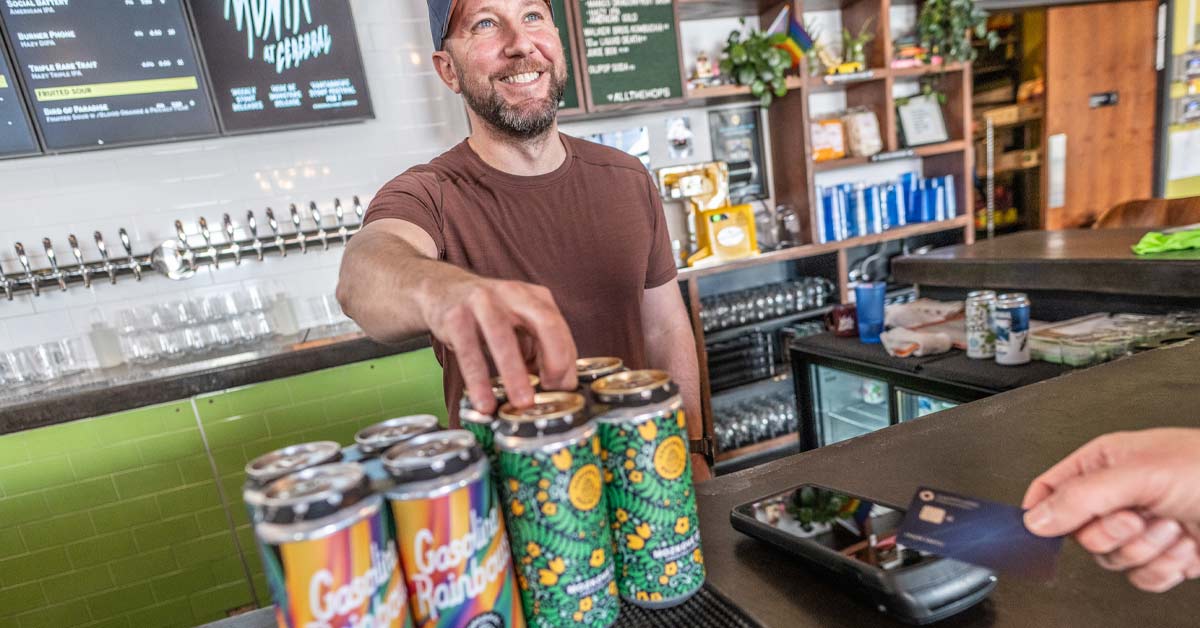 Taproom bartender ringing up beer to-go as customer pays with credit card