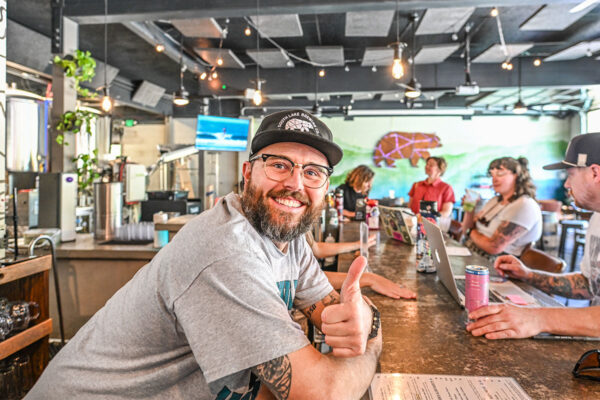 bartender leaning on a taproom bar and giving a thumbs up