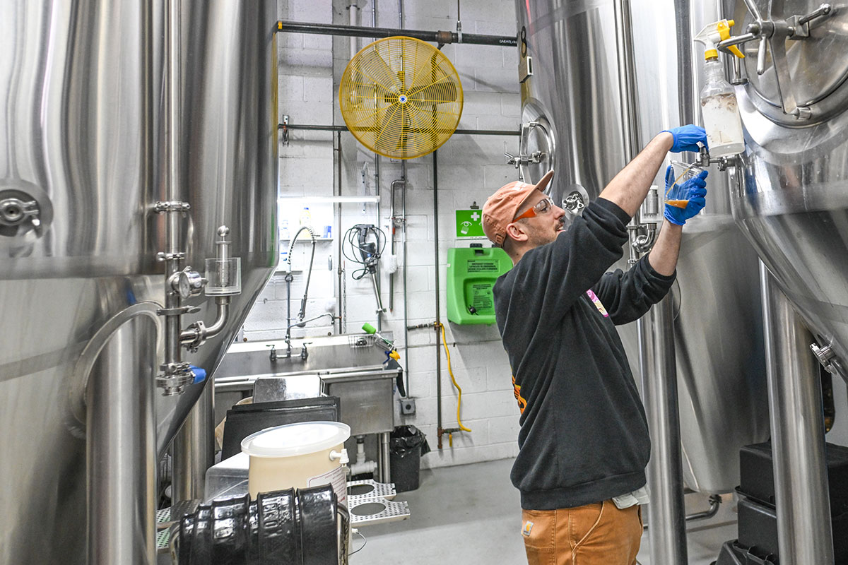 brewery worker among tanks in brewhouse