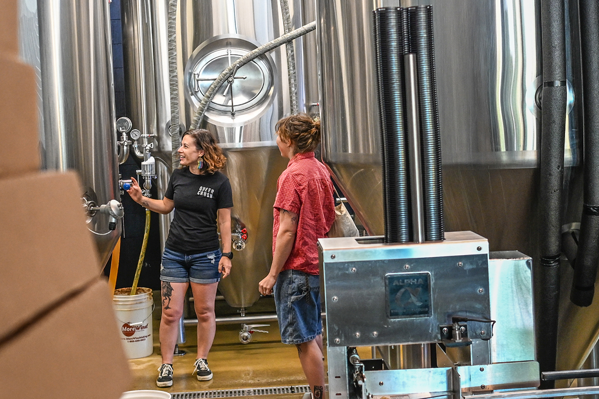 Two women brewery employees talking in a brewhouse.