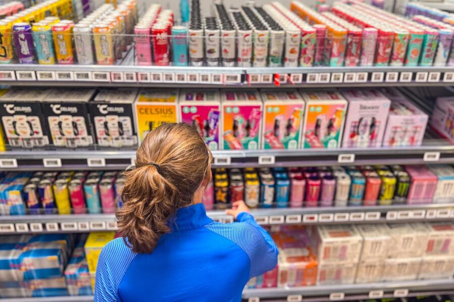 A woman shopping for energy drinks at a grocery store.