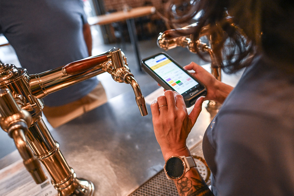 bartender using handheld POS system behind bar