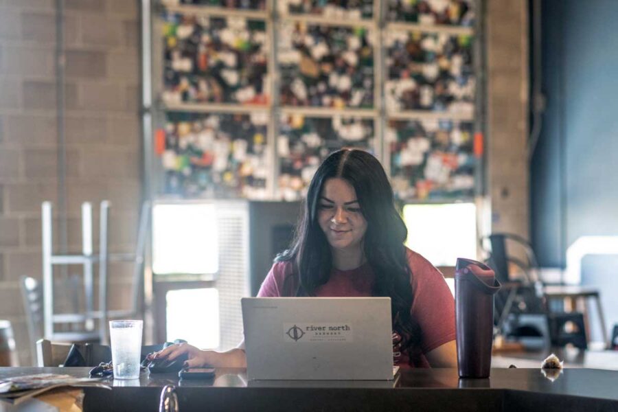 Brewery employee working on laptop at taproom bar