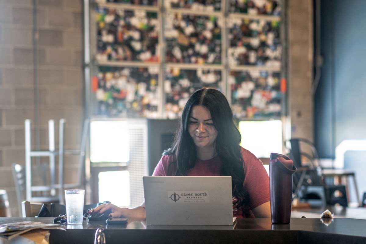 Brewery employee working on laptop at taproom bar