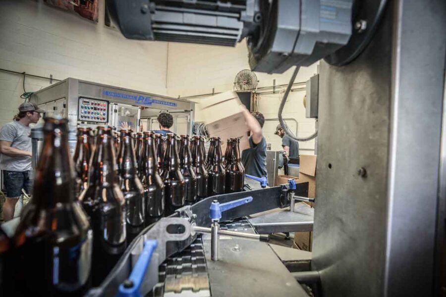Bottling line closeup with brewery workers in background