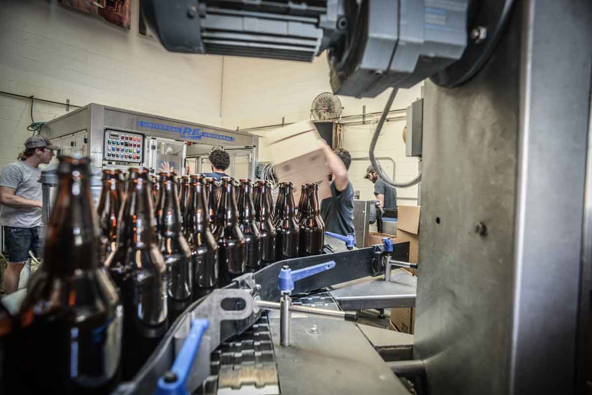 Bottling line closeup with brewery workers in background